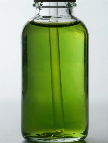 Avocado oil in a small bottle and bowl on a light, neutral background