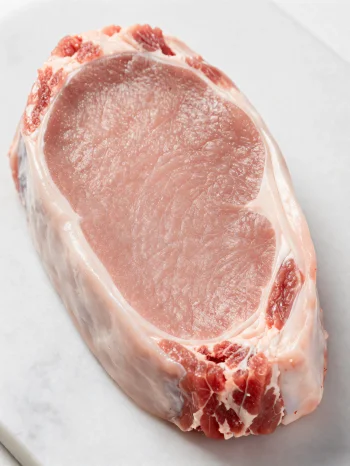 Fresh light-colored veal pieces with spices on a wooden cutting board
