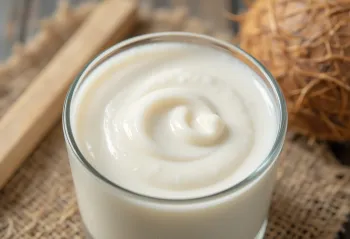 Freshly pressed coconut milk in a small glass bowl on a light background