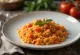 Creamy tomato risotto served with grated Parmesan in a white plate