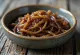 Bowl of spicy caramelized onion relish garnished with fresh chili.