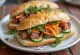 Bánh Mì Thịt Nguội cold cut sandwich served with fresh vegetables and cilantro.