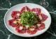 Venison carpaccio garnished with arugula and Parmesan