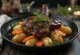 Roasted marmot meat served with root vegetables on a platter.